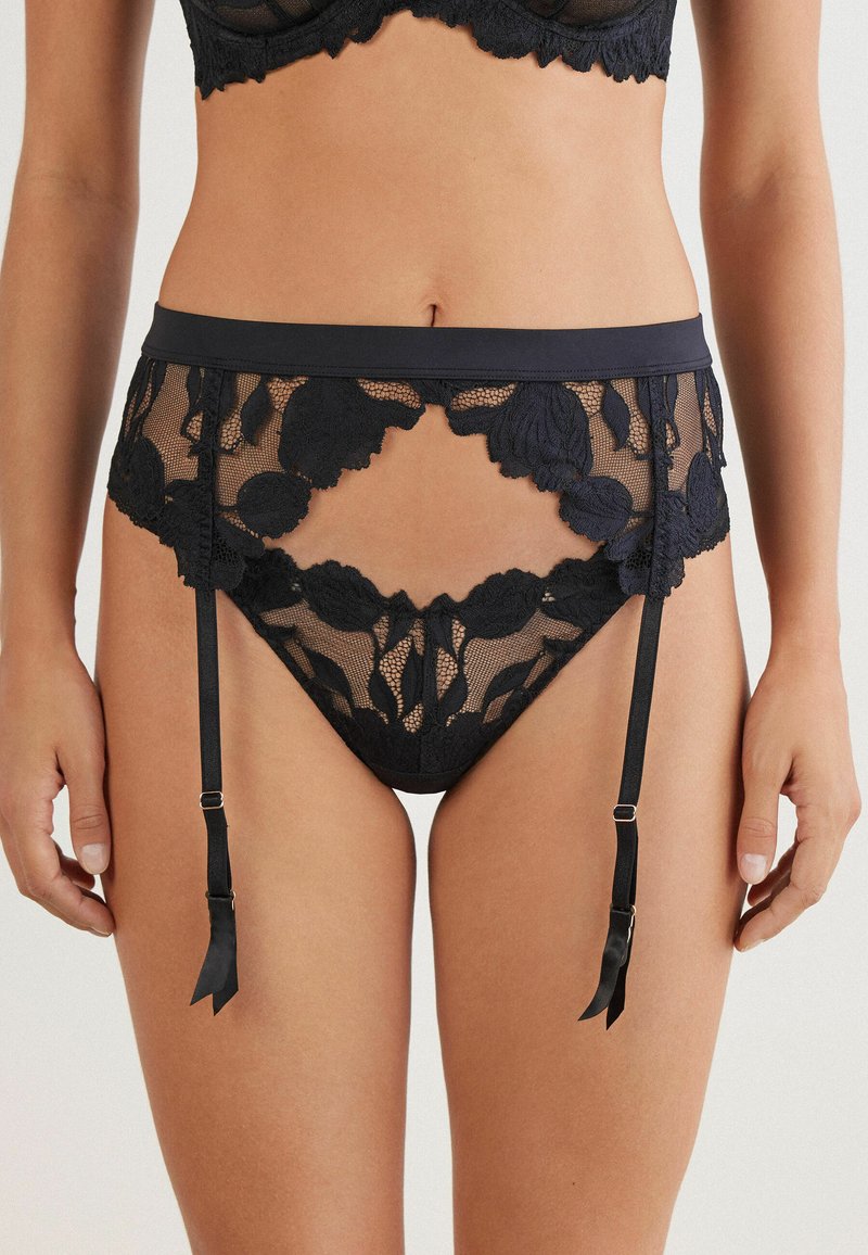Schwarzer Spitze-Gürtel mit floralen Mustern, ausgestattet mit einem breiten Taillenbund, transparenter Netzstruktur und verstellbaren Trägern mit Bandakzenten.