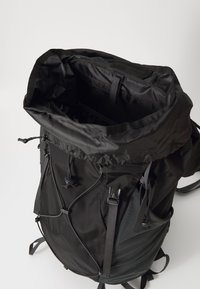 Sac à dos noir en tissu durable, doté d'une fermeture enroulable, de bretelles réglables et de plusieurs attaches extérieures pour l'équipement.
