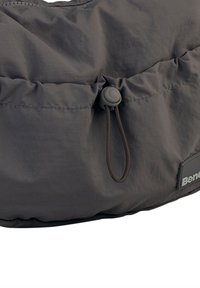 Donkergrijze puffer tas met een gestructureerd oppervlak, een verzamelde opening en een toggelsluiting. Bevat een gemerkte grijze patch voor identificatie.