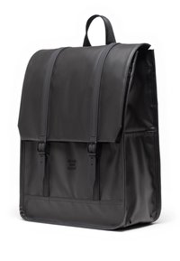 Zaino in pelle nera con chiusura a pattina, due cinturini frontali e un logo goffrato discreto. Texture liscia con una forma strutturata.
