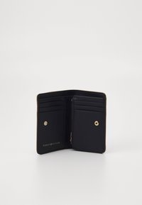 Svart skinnlommebok med flere kortrom, en glidelåscompartments og en gulltrykkknappforsegling. Har preget logo på innsiden.