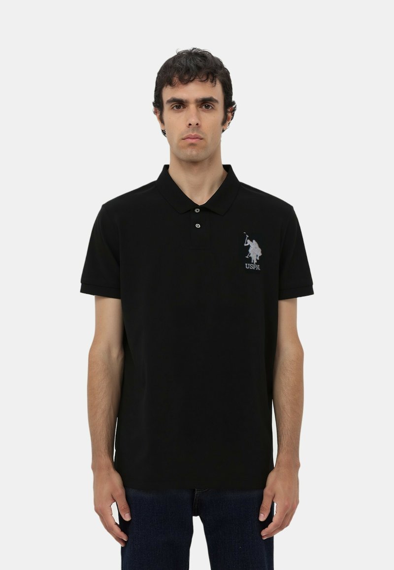Polo shirt nera in cotone, con patta a tre bottoni e maniche corte. Logo ricamato sul lato sinistro del petto.