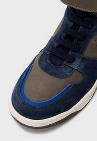 Navy and gray sneaker with suede and smooth leather, featuring a blue accent, lace-up closure, and textured rubber sole.
