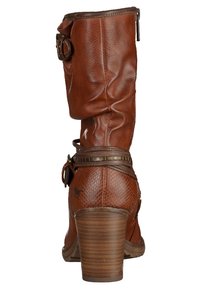 Brązowy skórzany botek do kostki z piętą na podwyższeniu, dekoracyjnymi skórzanymi paskami z ćwiekami oraz klamrą na górnej części cholewki.
