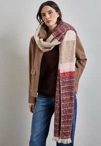 Sciarpa oversize in morbido materiale knit, caratterizzata da strisce multicolori di bordeaux, rosa e beige, con bordi frangiati.