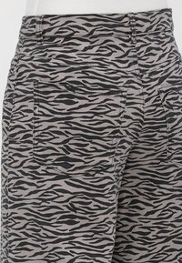 Pantalon gris avec motif de rayures de tigre noir, vue arrière montrant deux poches arrière et des passants pour ceinture à la taille.