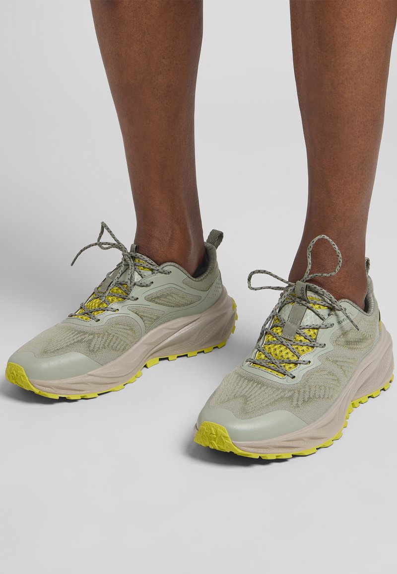Baskets de course vert clair avec dessus en maille et synthétique, accents jaunes, semelle texturée et lacets sécurisés pour un ajustement confortable.