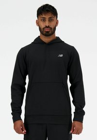 Sudadera negra de tejido suave, con un bolsillo frontal, capucha con cordón y un sutil logo en el pecho. Diseño liso y ajustado.