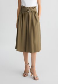 Gonna midi khaki con un design a pieghe, vita alta e una fibbia metallica rotonda. Indossata con sandali con tacco e cinturini, caratterizzati da un motivo testurizzato.