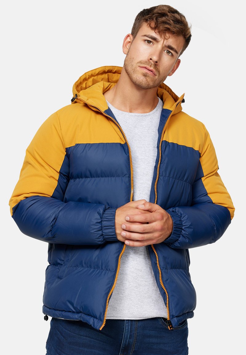 Blue and yellow puffer jacket with a zip closure, hood, and elastic cuffs. Features color-block design and smooth, shiny fabric texture.