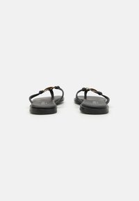 Pantofi flip-flop negri cu curele subțiri, având o piesă decorativă din metal auriu. Talpa este plată, cu un finisaj mat.