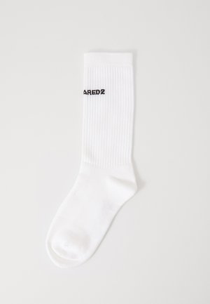 Chaussette en coton blanc présentant une texture côtelée, un bout rond et le texte "AREDZ2" brodé en noir près du haut.