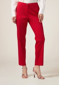 Punaiset räätälöidyt housut, joissa on sileä pinta, etupainike suljenta ja slim fit, yhdistettyinä metallisiin nauhakenkiin, joissa on korkeat korot.
