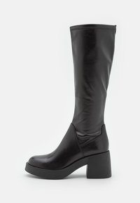 Botas negras hasta la rodilla hechas de cuero sintético liso. Presentan una puntera redondeada, tacón cuadrado y detalle de costura a lo largo del eje.