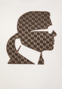 Ricamo a motivi neri e marroni raffigurante la silhouette di un profilo su sfondo bianco; presenta una coda di cavallo e occhiali.