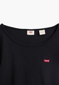 Svart kortermet T-skjorte med rund hals og en liten rød Levi's-logo på venstre bryst. Stoffet ser glatt og lett ut.