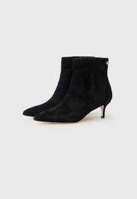 Stivaletti alla caviglia in suede nero con punte affusolate e tacchi kitten, con una sottile decorazione dorata sul lato, esposti su uno sfondo bianco.