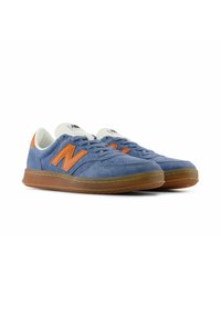 Blue suede sneakers with orange accents and white laces. Gum rubber outsole with visible stitching. Classic low-top design.