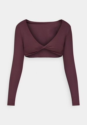 Long-sleeve, deep burgundy crop top made of smooth fabric, featuring a twisted front design and a wide V-neckline.
