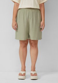 Lichtgroene, kniebrede shorts met een elastische tailleband. Gemaakt van een textuurstof. Gecombineerd met beige platform sandalen.