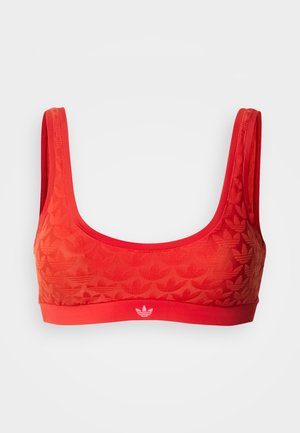 Κόκκινο αθλητικό σουτιέν με φαρδιές τιράντες, με ανάγλυφο μοτίβο από λογότυπα Adidas trefoil και μικρό λευκό λογότυπο στη κάτω ταινία.