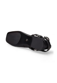 Zwarte hoge hak sandaal met een glad leren bovenwerk, vierkante neus, enkelband en metalen gesp accent. Gelaagd rubberen zool voor grip.