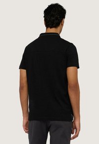 Czarna koszulka polo z krótkim rękawem, z delikatnym kołnierzykiem, o prostym wzorze, wykonana z bawełny, z prostym dołem i dyskretnymi detalami przeszycia.