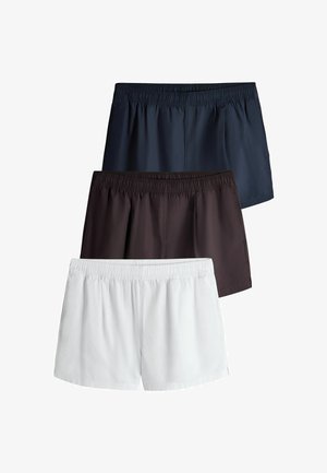 Drei Paare schlichte Shorts in Marineblau, Schwarz und Weiß mit elastischem Bund, vertikal auf weißem Hintergrund gestapelt.