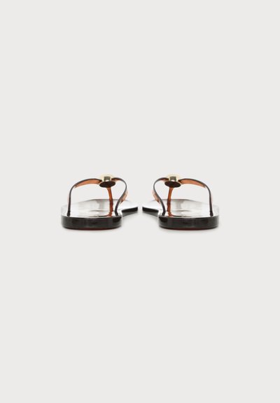 Paire de sandales plates noires avec fines lanières et ornements circulaires dorés, vues de face sur un fond clair uni.