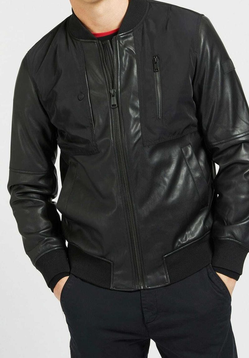 Giacca bomber nera in pelle, con zip frontale, polsini e orlo a coste, e tasche sul petto e ai lati con dettagli di cucitura in evidenza.