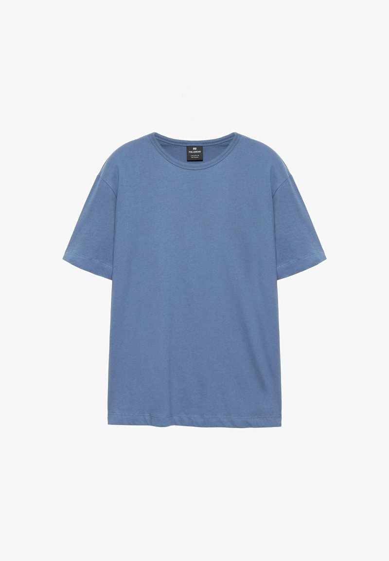 T-shirt bleu à manches courtes col rond suspendu sur un cintre blanc, design uni avec une petite étiquette noire à l’intérieur du col.