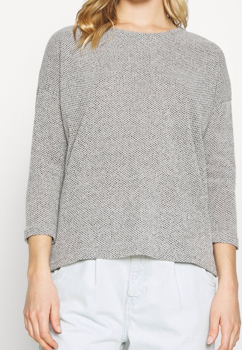 Ljusgrå stickad tröja med lös passform, rund halsringning och trekvartslånga ärmar. Strukturerat mönster med ribbade muddar.