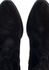 Svarta mockaankelboots med spetsiga tår, med subtila sömnadsdetaljer och slät textur. Designen är enkel och stilren.