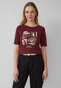 T-shirt court à manches courtes de couleur bordeaux présentant un graphique blanc abstrait et le texte "Embrace Your Uniqueness" (Acceptez votre unicité) sur le devant ; tissu lisse.