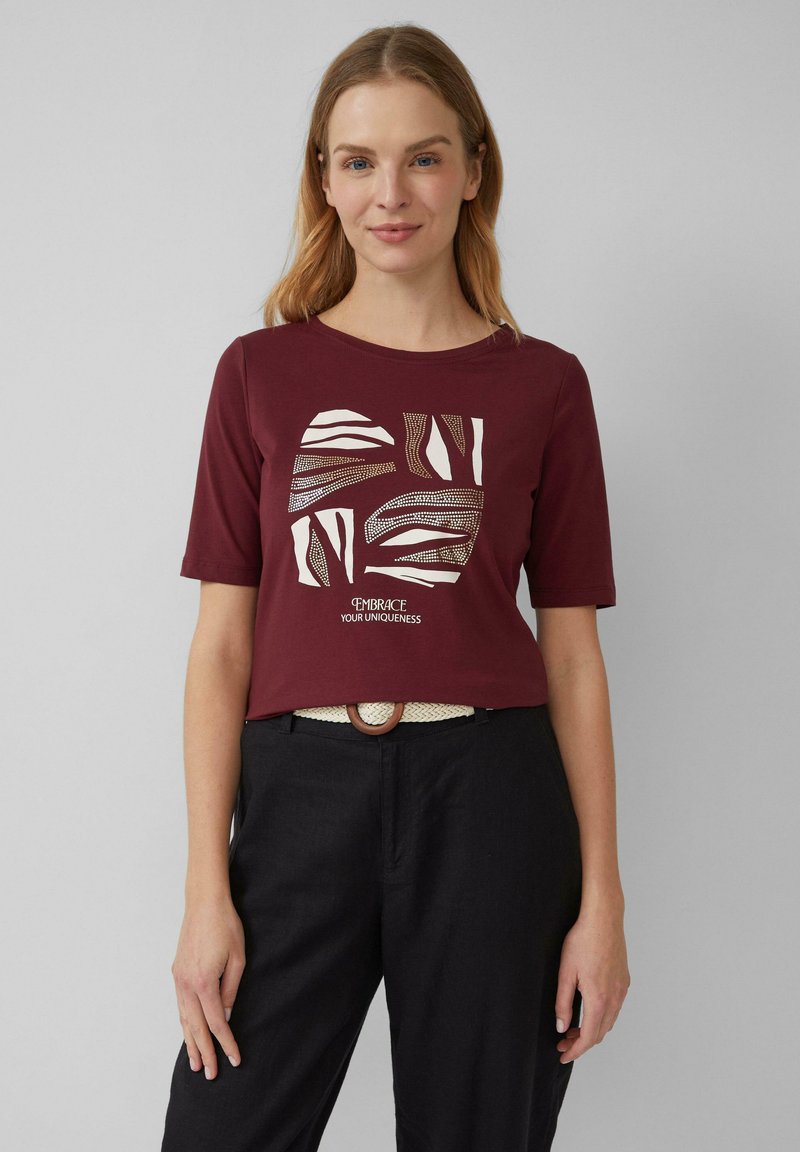T-shirt court à manches courtes de couleur bordeaux présentant un graphique blanc abstrait et le texte "Embrace Your Uniqueness" (Acceptez votre unicité) sur le devant ; tissu lisse.