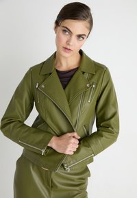 Veste de biker en simili cuir vert olive avec des fermetures à glissière asymétriques, des revers à cran et des détails matelassés sur les manches.