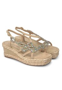 Sandales compensées beiges avec une semelle en jute tressé, dotées d'un design orné de bijoux sur les sangles et d'une semelle intérieure douce et texturée.
