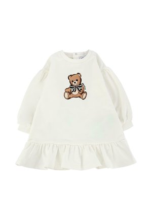 Robe blanche avec des manches bouffantes et un ourlet froncé. Présente un graphique d'ours en peluche brun avec un nœud noir et blanc à l'avant.