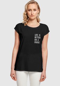 Sort kortærmet t-shirt lavet af bomuld, med hvid tekst der står "LIVET ER BEDRE PÅ EN KRYDSTOGT" på fronten.