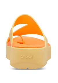 Yellow and orange platform sandals with cross-strap design. Made of lightweight material, featuring textured insoles and embossed "CROCS" logo.