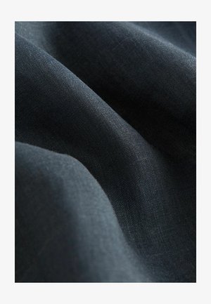 Tamsiai mėlyna medžiaga su lygiu paviršiumi, pasižyminti smulkiu pynimu ir švelnia blizgesiu, suformuota taip, kad parodytų savo lankstumą ir minkštumą.