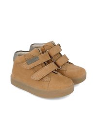 Zapatos de ante marrón de media caña que cuentan con dos amplias correas de Velcro, un forro suave en gris y una suela de goma texturizada.