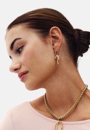 Set di gioielli in oro che comprende una collana a catena e orecchini pendenti coordinati, caratterizzati da una finitura liscia e lucida e forme astratte.