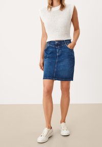 Top blanco ligero de punto con dobladillo acanalado combinado con una falda lápiz de mezclilla azul que presenta bolsillos frontales y una silueta ajustada.