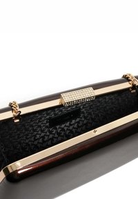 Black patent leather clutch bag with a gold-toned frame, embellished clasp, and textured interior featuring a patterned fabric lining.