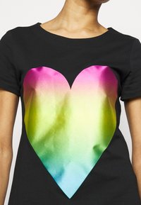T-shirt nera con una grande grafica a forma di cuore, che sfuma dal rosa nella parte superiore al verde e poi al blu nella parte inferiore, con una texture liscia.
