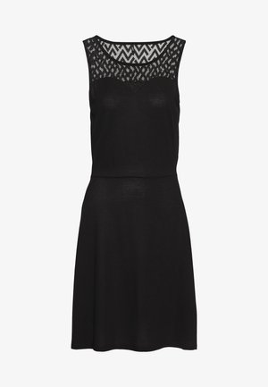 Bezramenné černé šaty s přiléhavým živůtkem, rozšířenou sukní a krajkovým vzorem na dekoltu a horní části hrudníku.