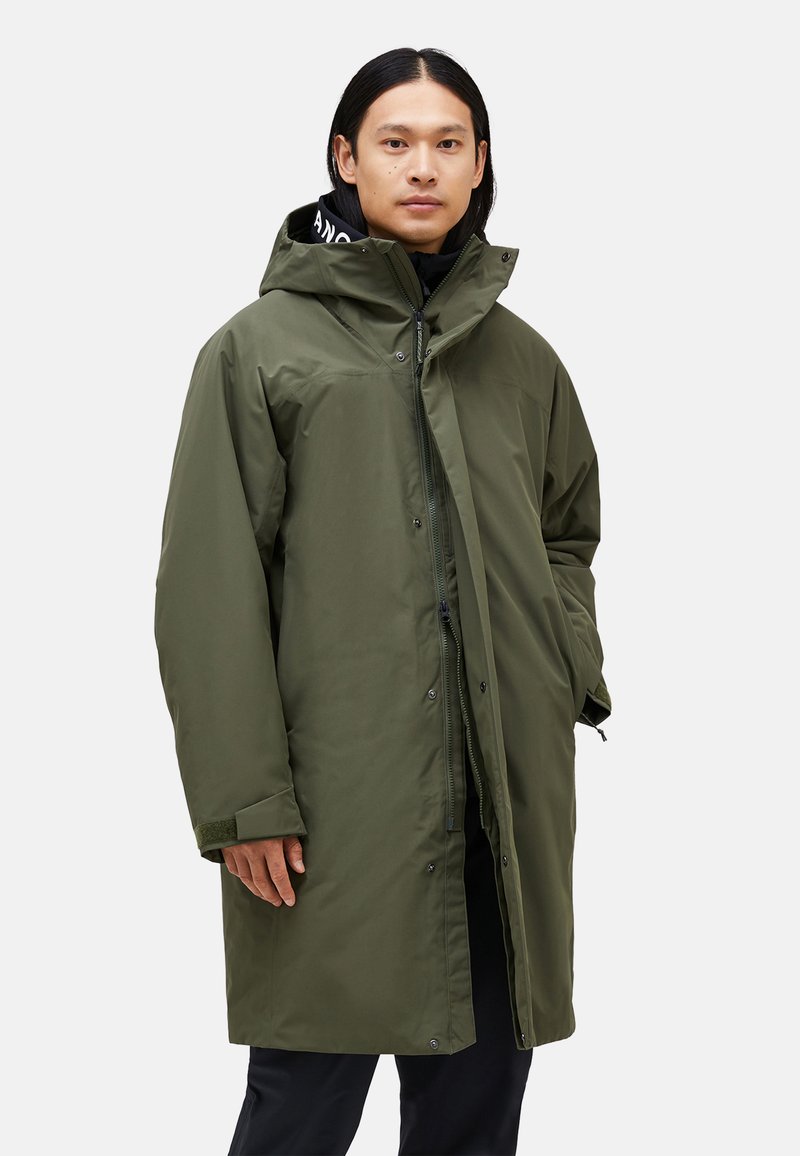 Green, waterproof parka with a hood, featuring a zip closure and snap buttons, textured fabric, and side pockets.