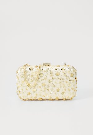 Petite pochette rectangulaire crème ornée de sequins floraux dorés et dotée d'une bandoulière chaîne dorée, posée sur un fond clair uni.