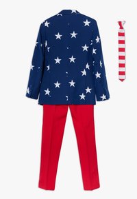 Sinise kangas valgete tähtedega bleiser, mis on kombineeritud punaste pükstega; küljes on punase ja valge triibulise lipsu. 